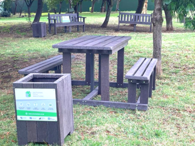 Range of recycled plastic furniture, including park benches, picnic table and rubbish bin.