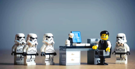 Star wars lego characters surrounding a nervous looking character behind a desk