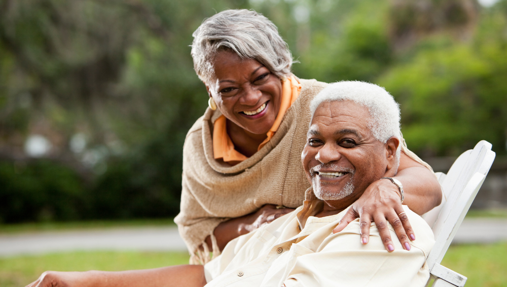 A smiling senior African couple outside