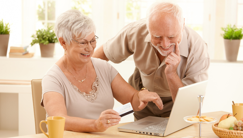 A smiling senior couple looking at a laptop.
