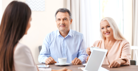 A smiling senior couple sitting across the table from a younger lady